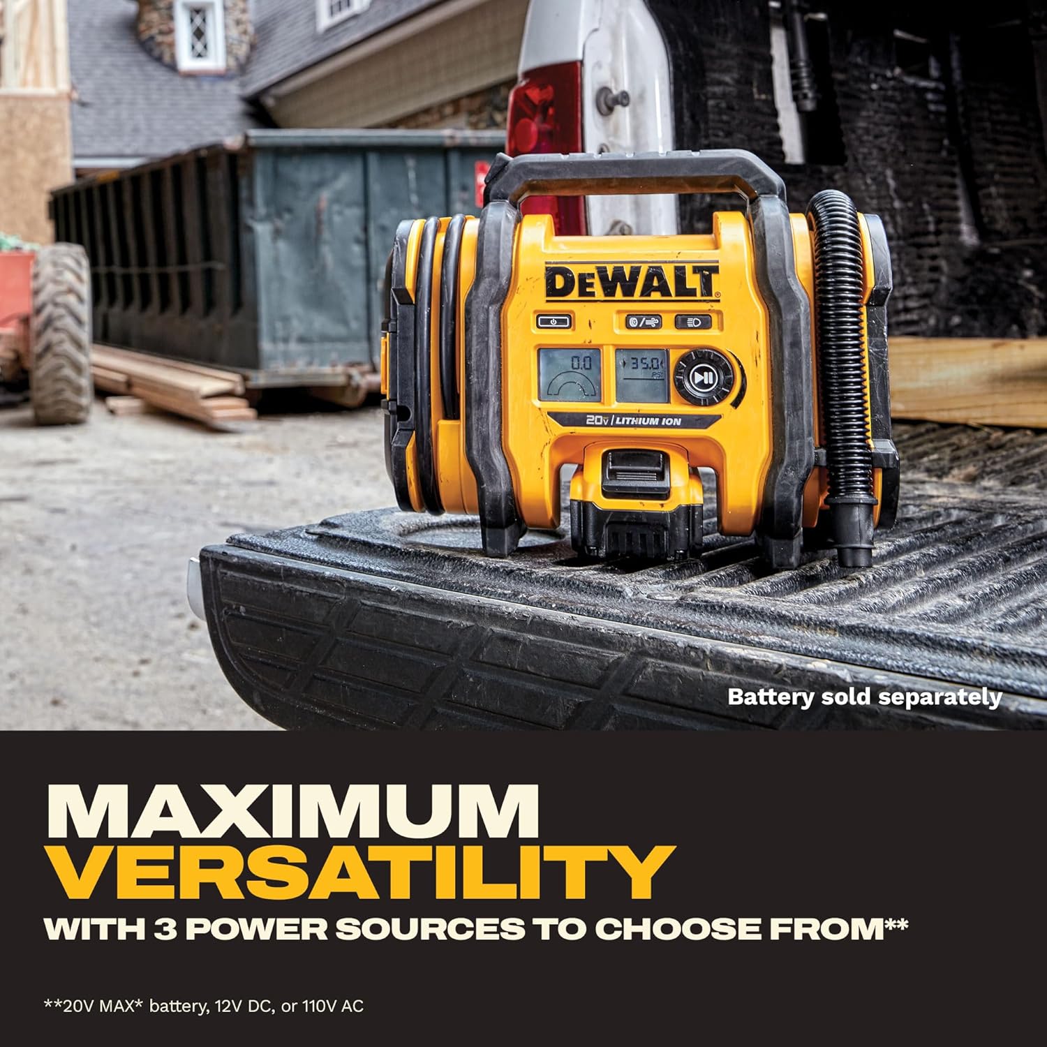 The inflator standing in the bed of a pickup on a building site, hose coiled on the body